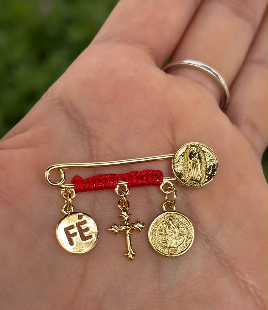 Prendedor con hilo rojo, dije Fé, cruz, San Benito y Virgen.